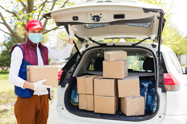Grocery delivery man wearing medical gloves and face mask. Online shopping and delivery for grocerys, wine and food. Self Quarantine during coronavirus pandemic. Food delivery service courier - 写真・画像
