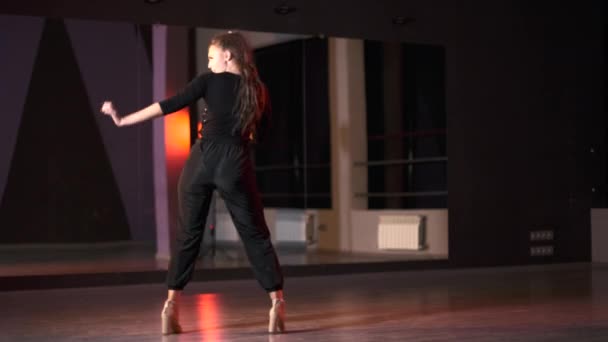 Пластиковая молодая женщина на высоких каблуках танцует современный танец, фристайл в танцевальной студии перед зеркалом.  - Кадры, видео