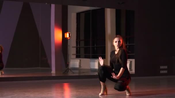 Πλαστική νεαρή γυναίκα με ψηλά τακούνια χορεύει μοντέρνο χορό, freestyle σε ένα στούντιο χορού μπροστά από έναν καθρέφτη. - Πλάνα, βίντεο