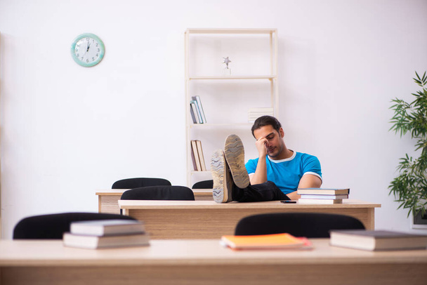 Estudante masculino exausto se preparando para os exames em sala de aula - Foto, Imagem