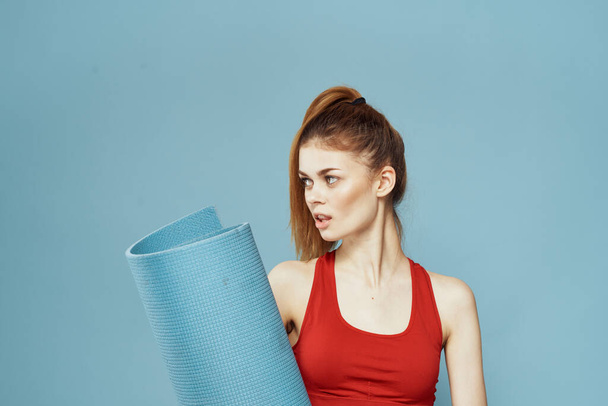 femme athlétique avec tapis de fitness exercice mince figure rouge t-shirt fond bleu - Photo, image