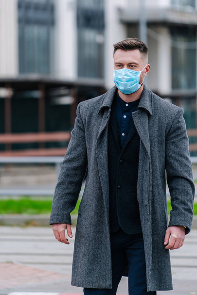 Elegant young businessman poses in city background in face protective mask. Epidemic in the world. - Fotoğraf, Görsel