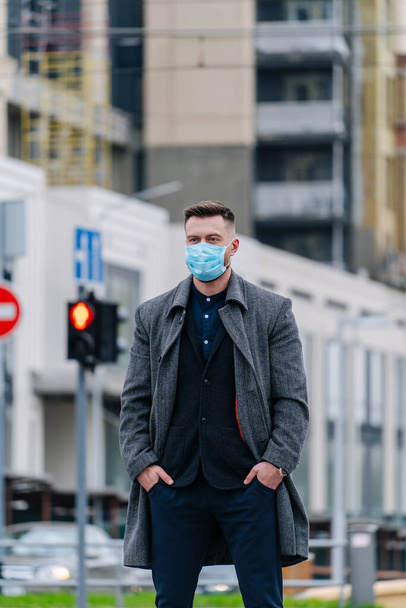 Businessman with a breathing mask crossing the street. Traffic light background. - Photo, image