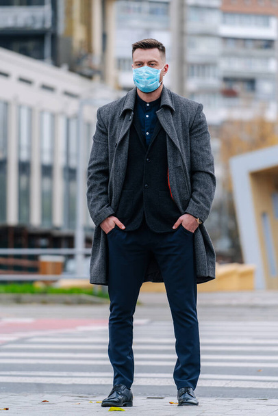 Portret van een knappe man met een beschermend masker, lopend in de stad. Man draagt een masker om ziektekiemen, giftige dampen en stof te voorkomen. Preventie van bacteriële infectie Corona virus pandemie. - Foto, afbeelding