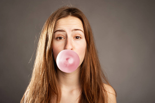 young woman making a bubble from a chewing gum - Photo, Image