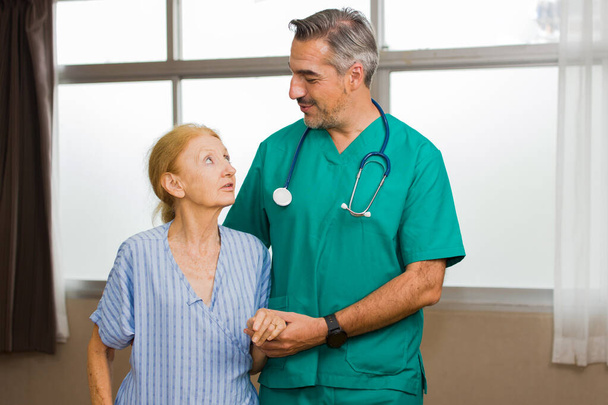 Az egészségügyi dolgozók egy idős beteget támogatnak.. - Fotó, kép
