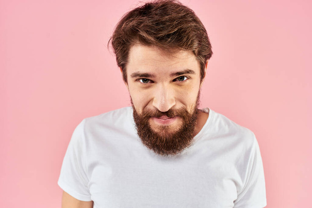 Bearded man in white t-shirt gesturing with hands facial expression close up pink background - Zdjęcie, obraz