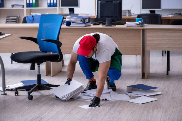 Jovem empreiteiro limpando o escritório - Foto, Imagem