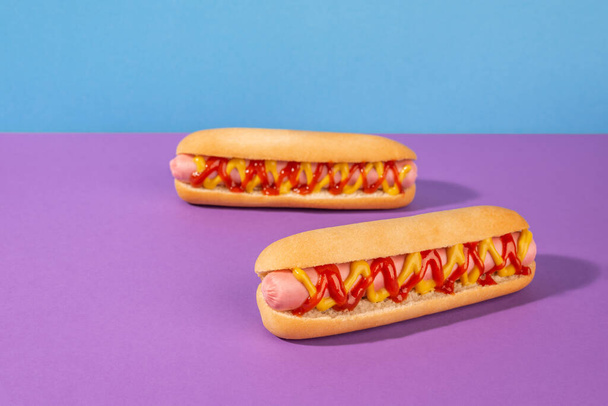 Couple of fresh hot dogs on violet background - Фото, изображение