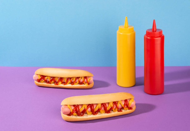 Two hotdogs and squeeze bottles of liquid mustard and ketchup - Foto, Imagen