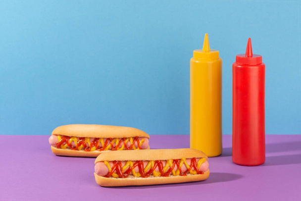 Two juicy hotdogs and squeeze bottles of mustard and ketchup - Foto, afbeelding