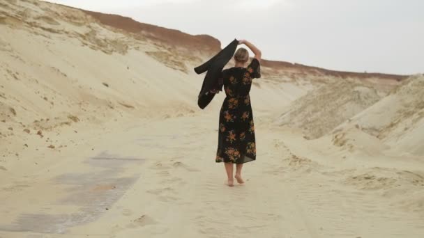 Rückenansicht einer barfüßigen Frau, die in der Wüste spaziert - Filmmaterial, Video