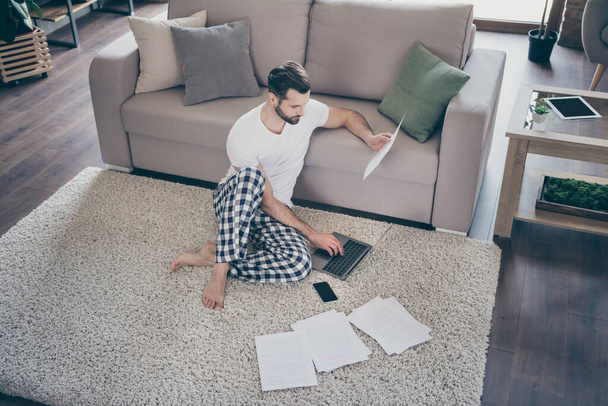 Top above high full length angle view photo of focused boss lawyer man sit carpet work remote laptop hold document analyze company development report in house indoors room - 写真・画像
