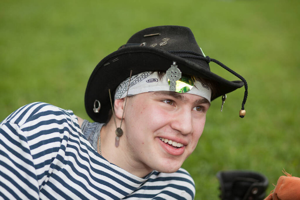 Moscow, Russia - July 1, 2020: Young attractive guy in hat smiling during Hippie Day in Tsaritsyno park. Hippy Day is celebrated in Tsaritsyno Park every year. - Foto, Imagem