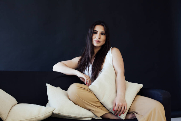 Portrait of a beautiful brunette woman in home clothes on the sofa - Φωτογραφία, εικόνα