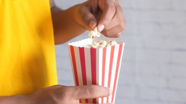 zbliżenie młody człowiek jedzenie popcorn  - Materiał filmowy, wideo