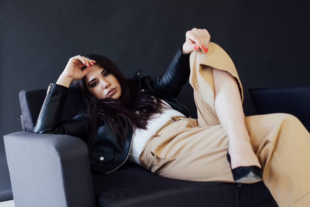 Portrait d'une belle femme brune orientale à la mode sur un canapé noir - Photo, image