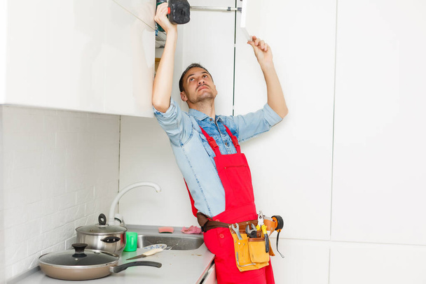 Yleismies korjata keittiön kaappi ruuvimeisselillä - Valokuva, kuva