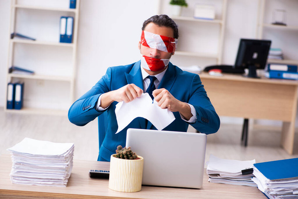 Mond en ogen gesloten mannelijke werknemer werken in het kantoor - Foto, afbeelding