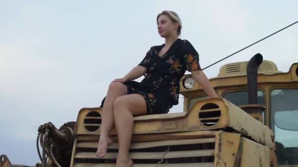 Босонога блондинка сидить на старому тракторі
 - Кадри, відео