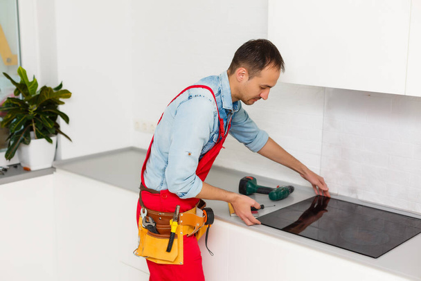 reparador adulto reflexivo reparación de estufa eléctrica en la cocina - Foto, Imagen
