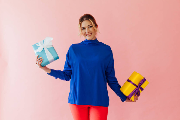 Beautiful woman of 40 years holding gifts on a pink background - Foto, Imagem