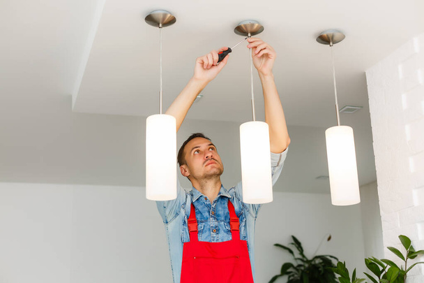 Рабочий электрик устанавливает потолочную лампу - Фото, изображение