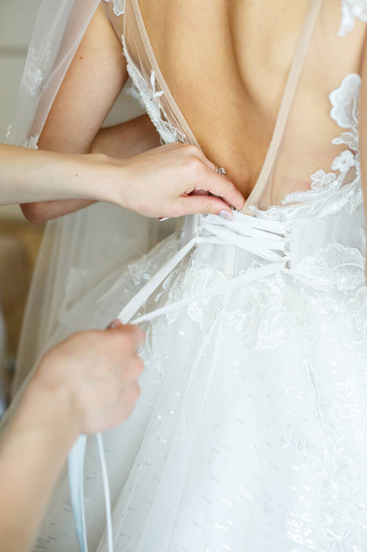 de bruid houdt in haar handen een mooie trouwjurk - Foto, afbeelding