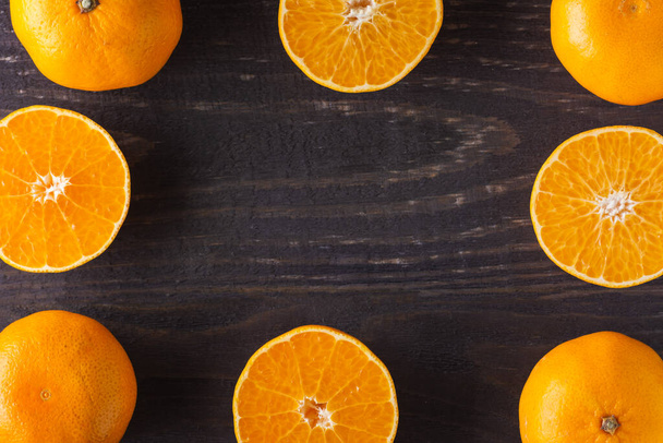 Fresh cut tangerines are laid out in a frame close-up. Copy space in the center. - Foto, imagen