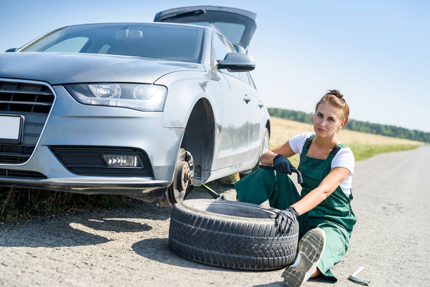 Nainen univormussa töissä auton jarrujen huollossa. Auton korjaus. Turvallisuustyö - Valokuva, kuva
