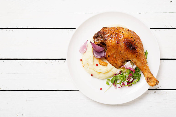 Roasted duck leg confit with mashed potatoes and fresh salad. - Фото, зображення