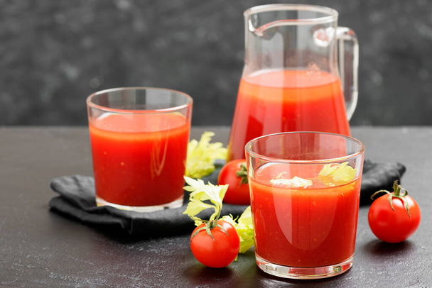 Томатний сік у склянці з селерою, вишневий помідор на темному фоні
. - Фото, зображення