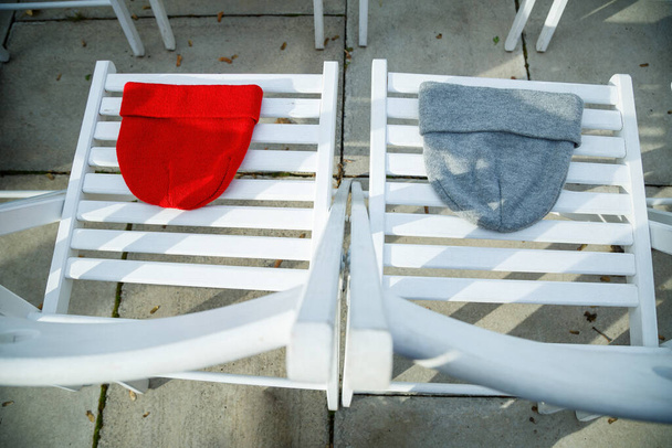 Deux chapeaux de rouge et gris sur des chaises blanches - Photo, image