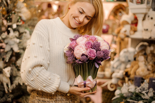 beautiful woman holding cute flower arrangement in white and purple colors - Photo, image