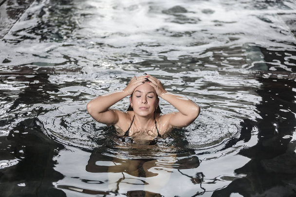 Високий кут спокійної молодої жінки отримує спа-ванну в басейні з чистою водою під час відпочинку у вихідні в оздоровчому центрі
 - Фото, зображення