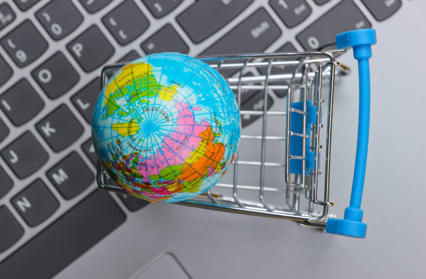 Supermercado global en línea. Carro de la compra con globo en teclado portátil. - Foto, imagen