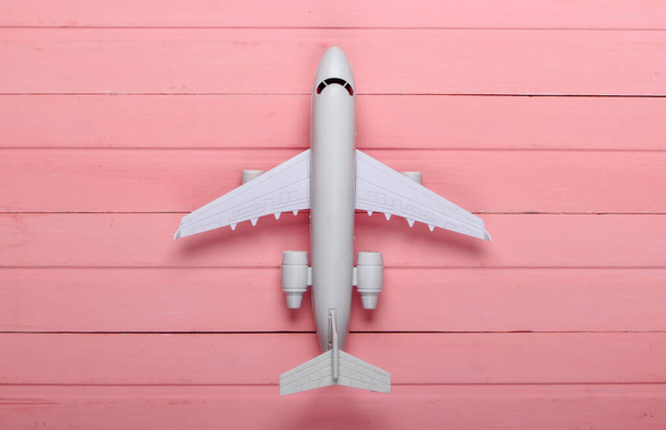 Αεροπορικός τουρισμός ή ταξίδια επίπεδη θέσει. Αεροπλάνο ειδώλιο σε ροζ ξύλινο φόντο. Άνω όψη - Φωτογραφία, εικόνα