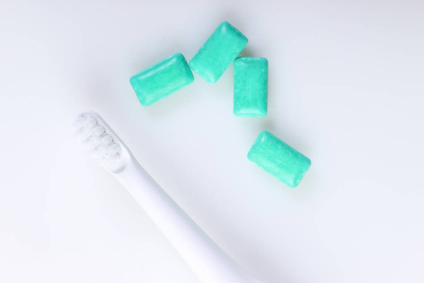 Cepillo de dientes con goma de mascar sobre fondo blanco. Cuidado de la salud dental, aliento fresco. Vista superior - Foto, imagen