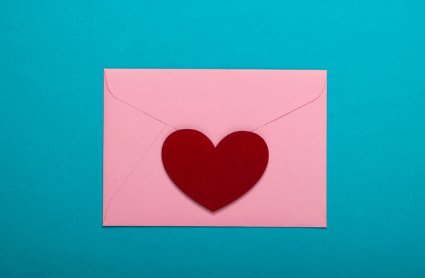 Umschlag mit rotem Herz (valentines) auf blauem Hintergrund. Valentinstag. Ansicht von oben - Foto, Bild