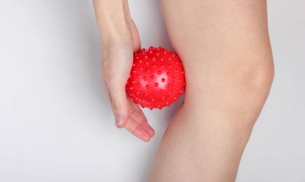 vrouw massages een massage bal onder haar knie. - Foto, afbeelding