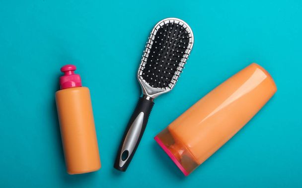 Shampoo bottles, hair conditioner, hair brushes on blue background. Hair care. Hygiene. Beauty flat lay - Photo, Image