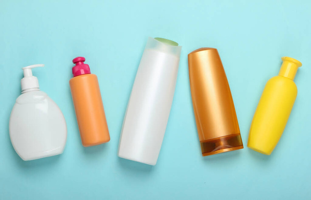 Shampoo bottles on blue pastel background. Hair care. Hygiene and cosmetics. Beauty flat lay. Top view - Photo, Image