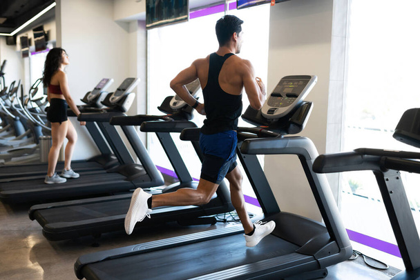 Handsome hispanic man looking out the window and exercising in a running machine  - Photo, Image
