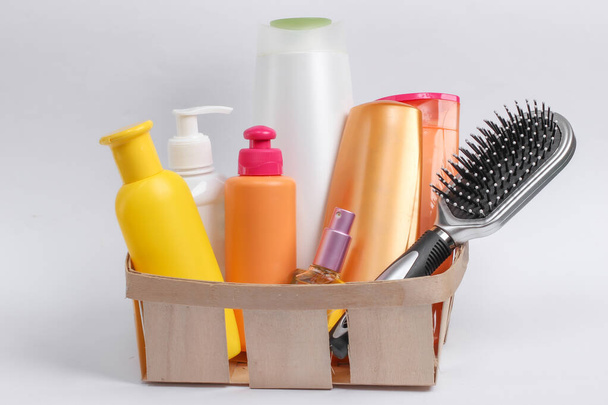 Láhve kosmetiky, šampony, hřeben v dřevěném koši na bílém pozadí. Kosmetické výrobky - Fotografie, Obrázek