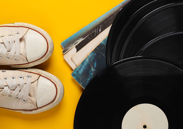 Vinyl record albums and retro sneakers on yellow background. Top view - Photo, Image