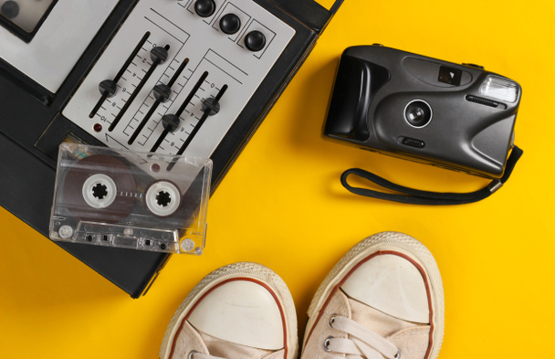 Old audio cassette player with retro sneakers, camera on yellow background. Retro media. Top view. - Valokuva, kuva