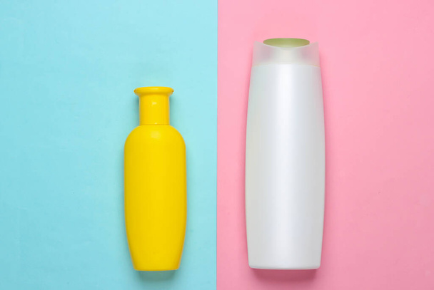 Two bottles of shampoos on a pink-blue pastel background. Top view - Photo, Image