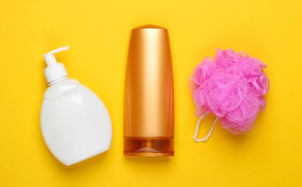 Bath, beauty products on yellow background. Shower gel, shampoo bottle, sponge. Top view. Flat lay - Photo, Image