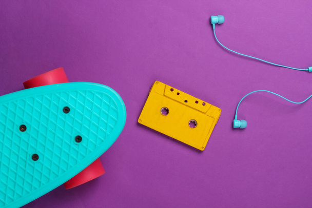 Cruiser board and retro audio cassette, earphones on purple background. 80s. Top view. Minimalism. - Foto, Imagem