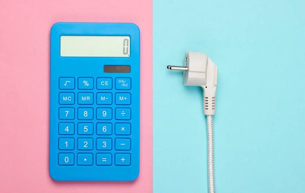 Kalkulator z wtyczką zasilania na różowym niebieskim tle. Obliczanie kosztów zużycia energii. Widok z góry - Zdjęcie, obraz